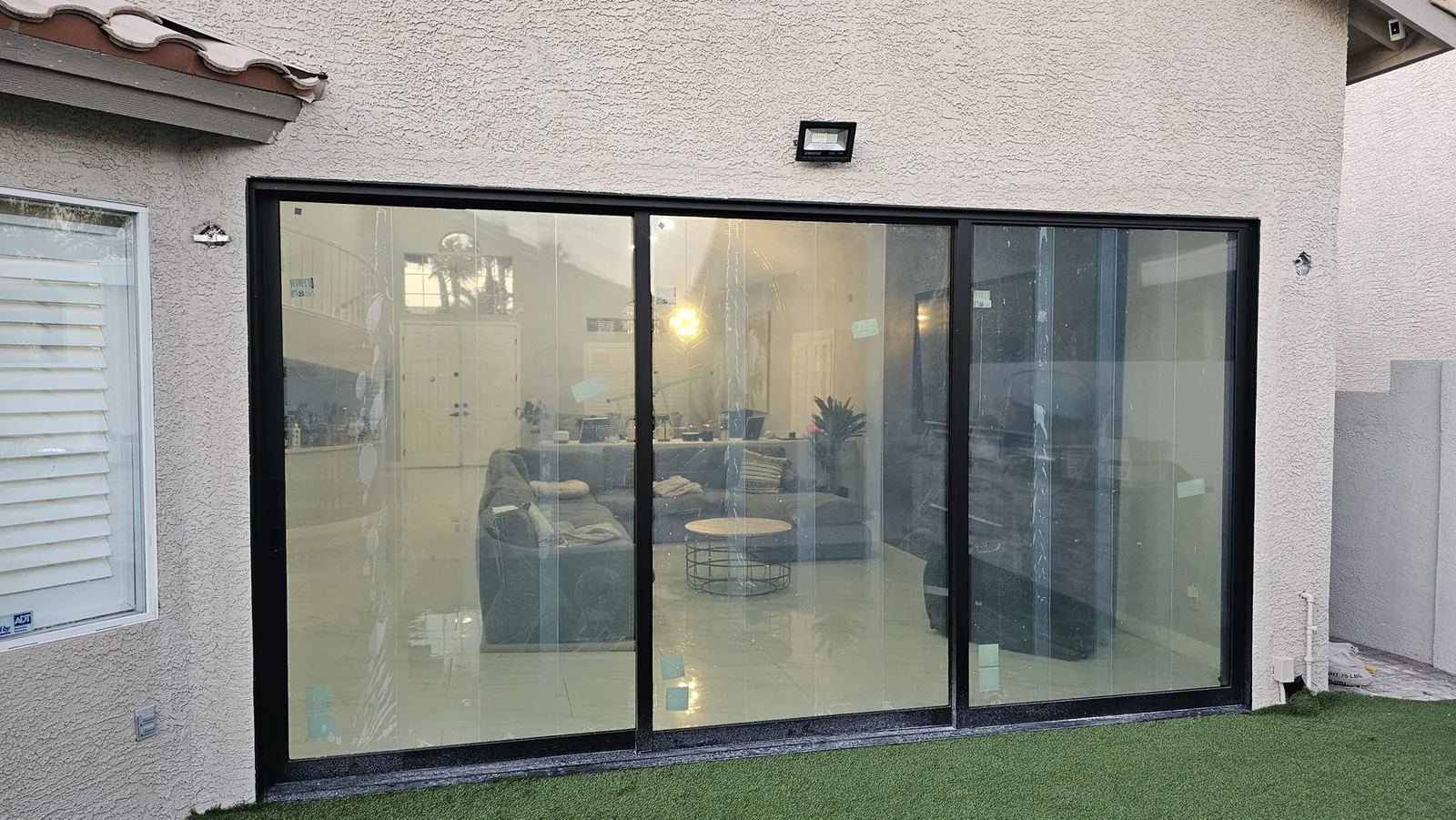 New black framed sliding patio door across the back of a stucco home