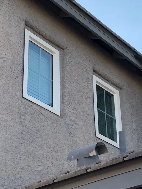 New white retrofit windows on the upper floor of a stucco home