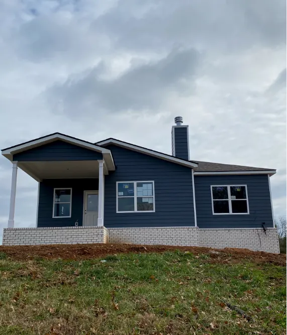 Blue sided new home with white windows and a covered front porch