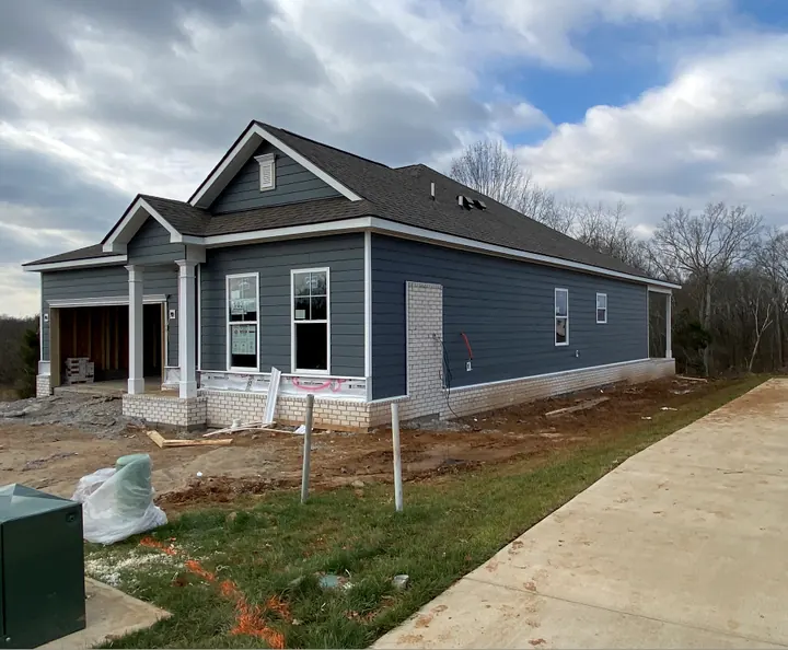 New blue sided home with white vinyl windows beside a fresh sidewalk