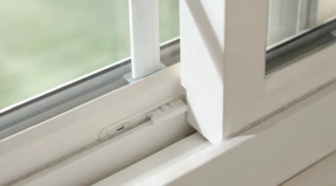 Close up of a white sliding window sash running in its track