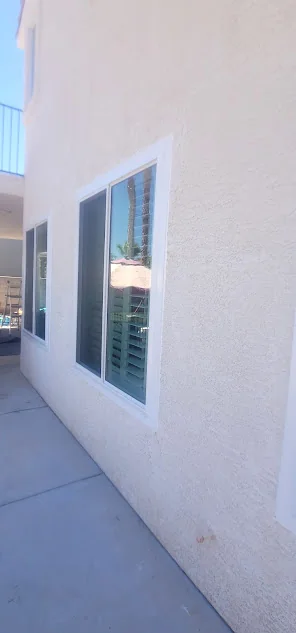 New white-framed sliding window installed in a stucco exterior wall