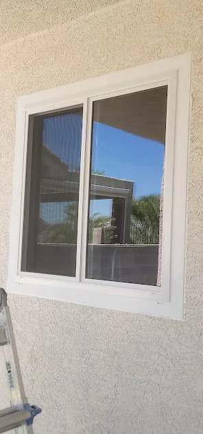 White vinyl sliding window set into a light stucco wall