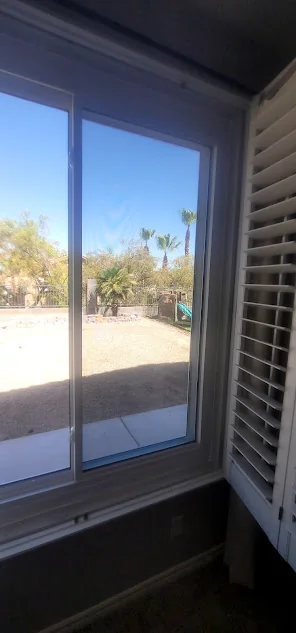 Interior view of a new sliding window looking onto a sunny backyard