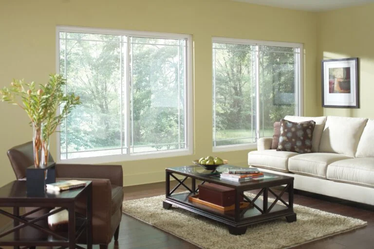 Living room with large white sliding windows and garden views